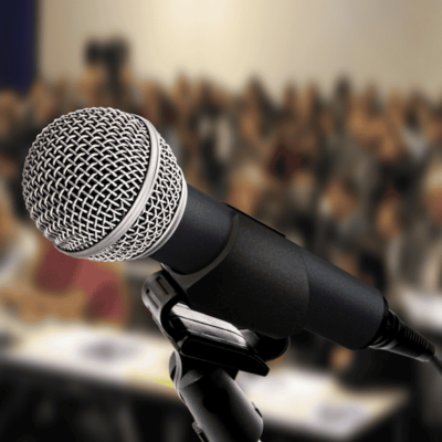 Close-up of a microphone in front of a large audience