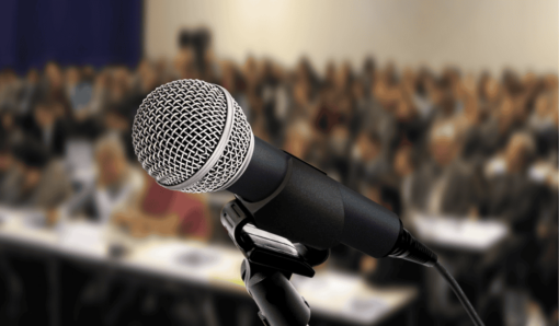 Close-up of a microphone in front of a large audience
